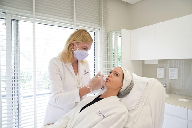 The doctor is enhancing the patient’s cheekbones with Dermal Fillers